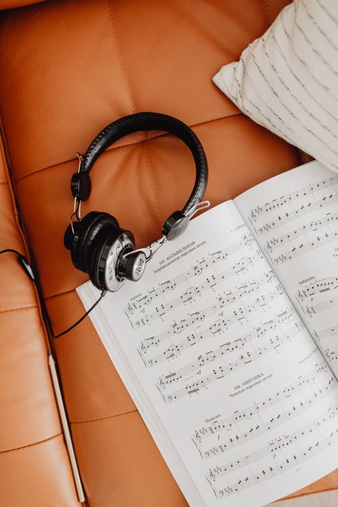 Black headphones resting on music sheets over a tan leather sofa.
