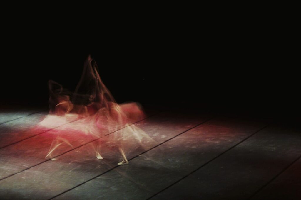 Artistic long exposure of a ballet dancer in motion, showcasing dynamic movement on stage.